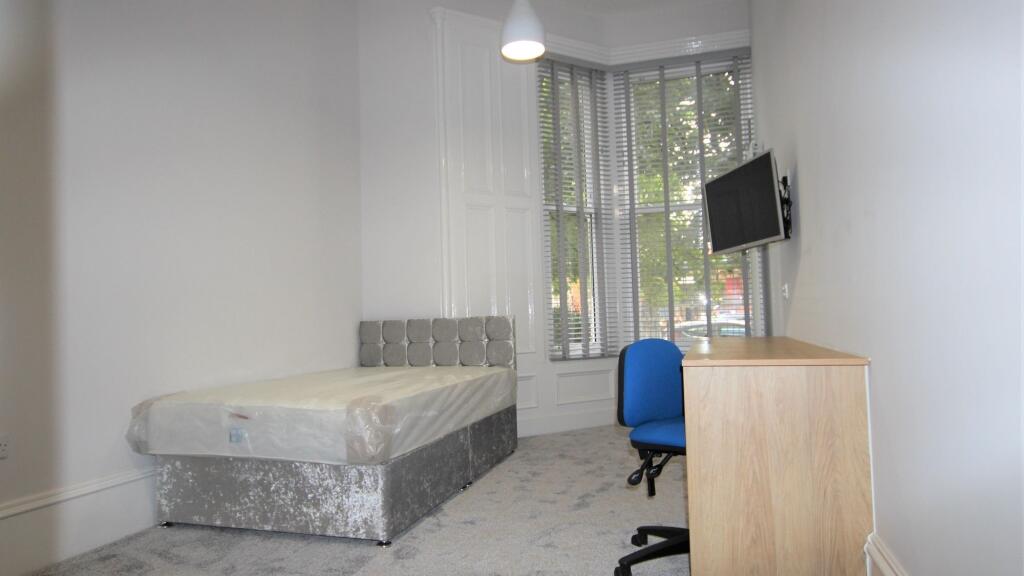 A bright single bedroom with a modern bed and a...