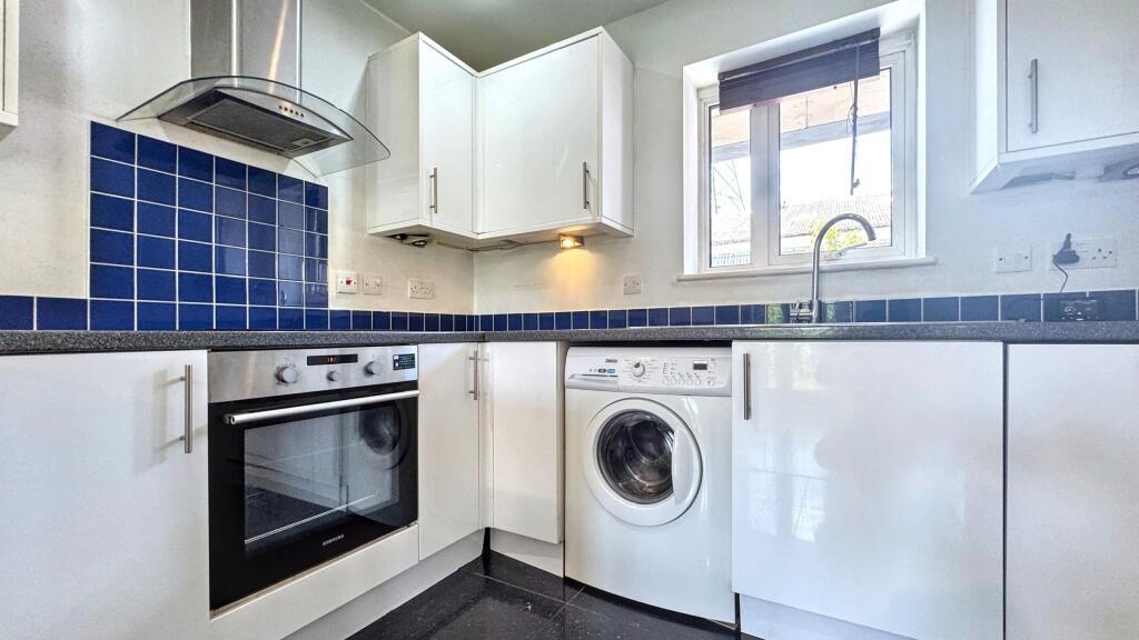 A modern kitchen featuring white cabinetry, a b...