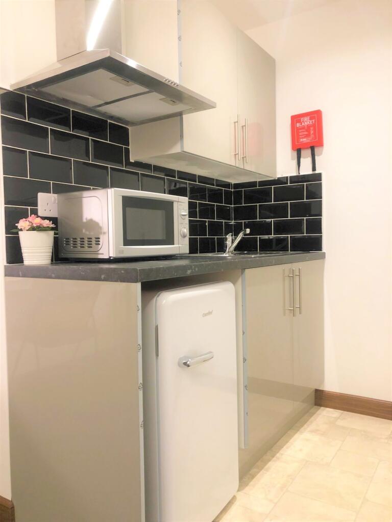 A modern, compact kitchen featuring sleek black...