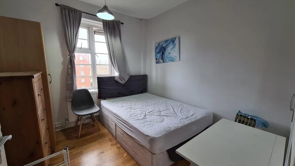 A tidy double bedroom with a large window allow...