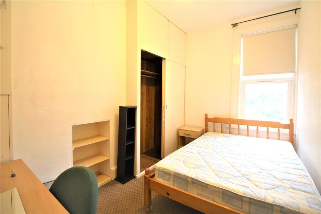 A simple, well-lit single bedroom featuring a w...