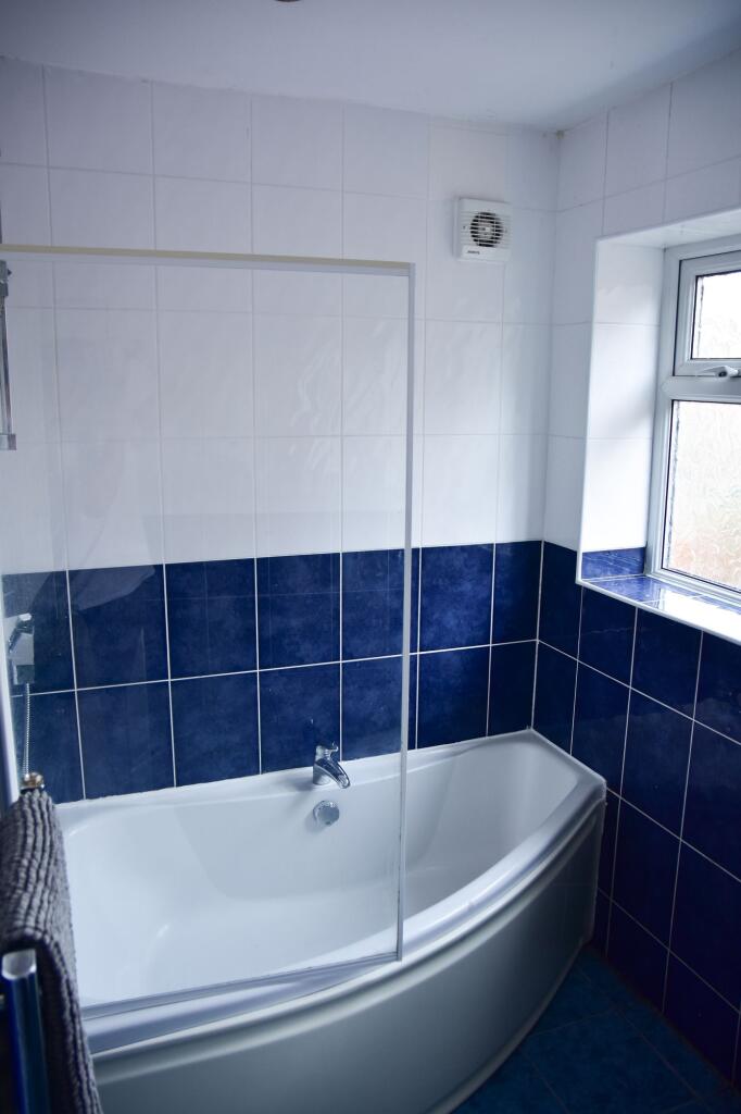 Bright, clean bathroom featuring a bathtub with...