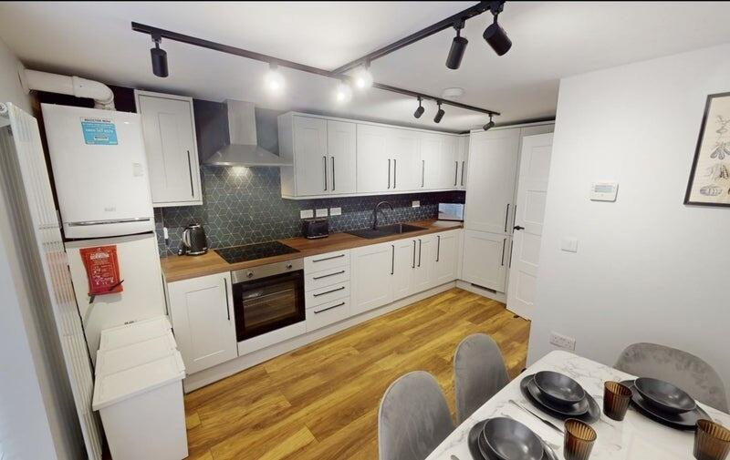 Modern fitted kitchen with white cabinetry, woo...