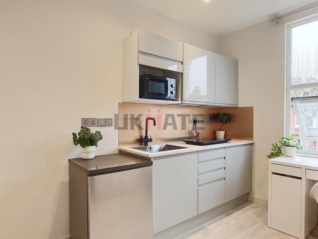 Modern kitchen with sleek white cabinetry, a co...