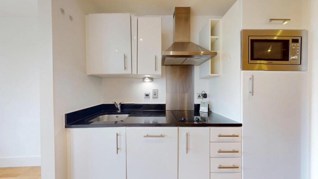 A modern and clean kitchen featuring white cabi...