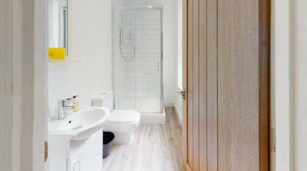 A modern, pristine bathroom featuring a walk-in...