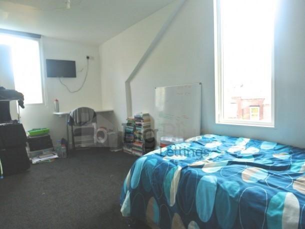 A cozy single bedroom featuring a bed with patt...