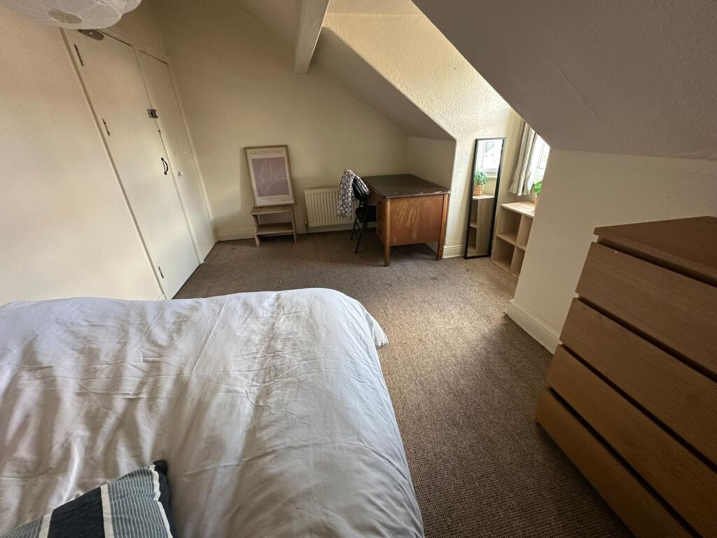 A cozy bedroom with a sloped ceiling, featuring...