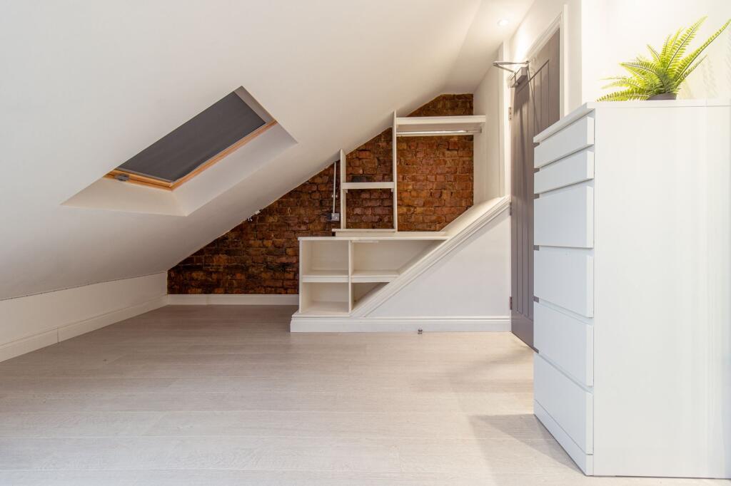 Bright, well-finished loft bedroom with a skyli...