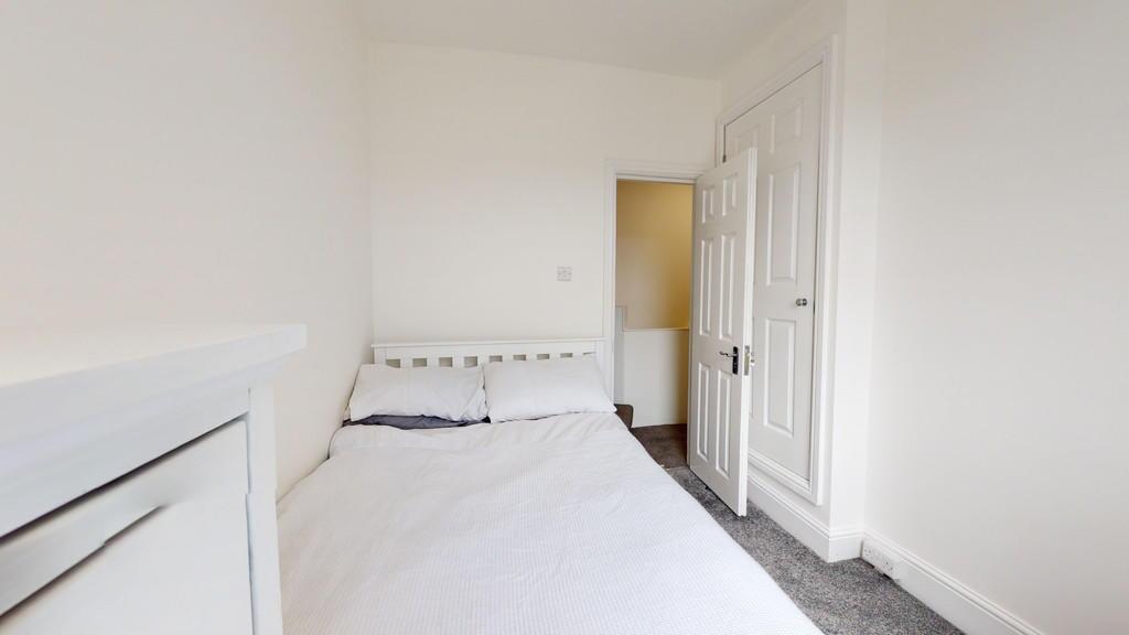 A bright and clean bedroom with white walls and...