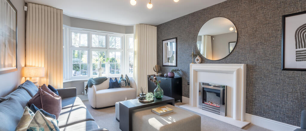 Modern living room with large bay window, grey and white furnishings, decorative cushions, and a fir