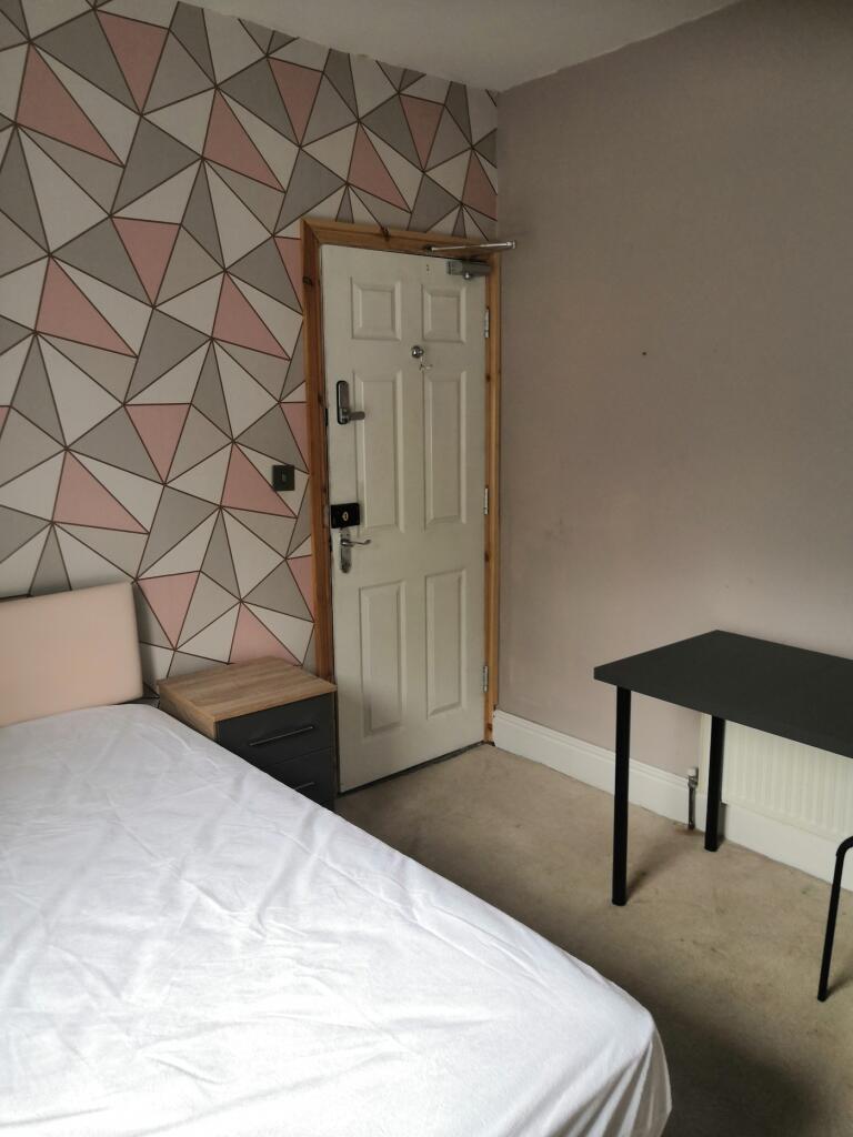 A neat double bedroom featuring a geometric pat...