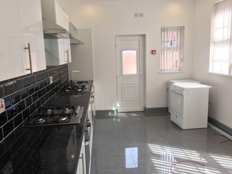 Bright modern kitchen with sleek black tiled sp...