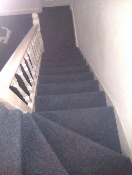 Carpeted staircase with painted balustrade and ...
