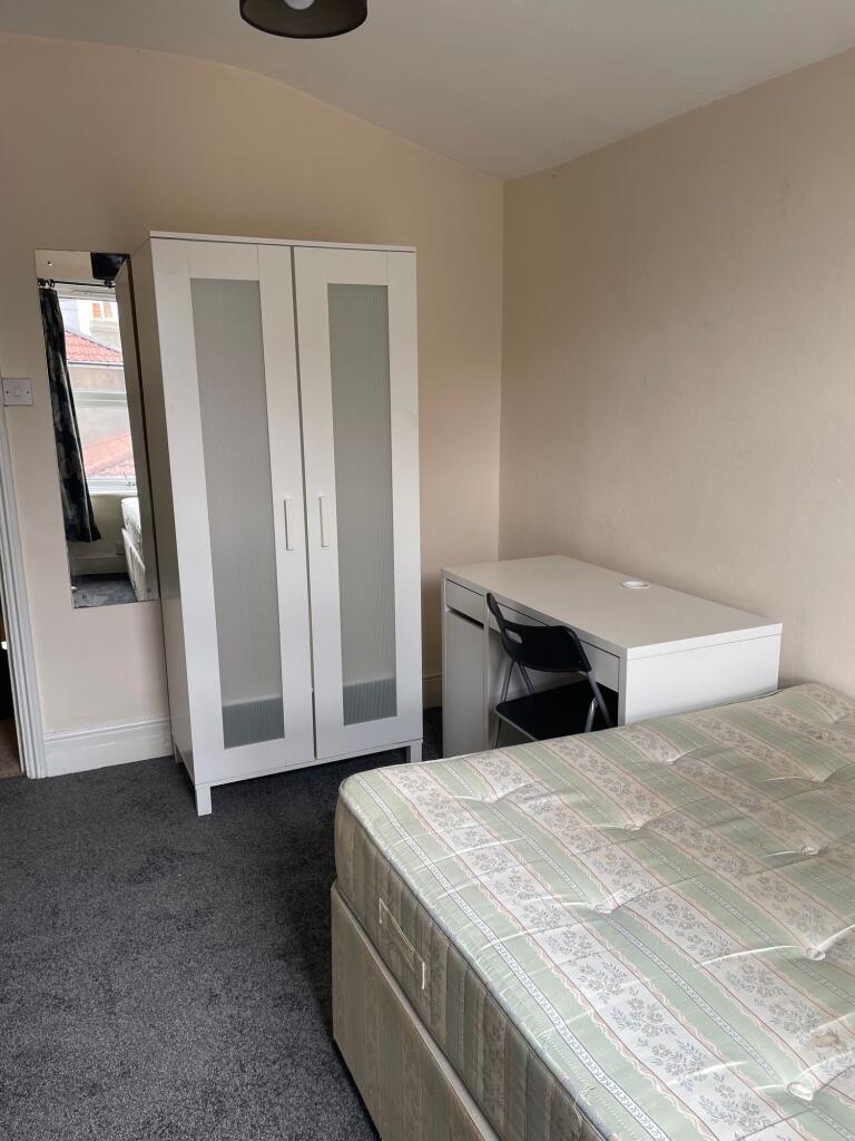 A cozy single bedroom featuring a sturdy wardro...