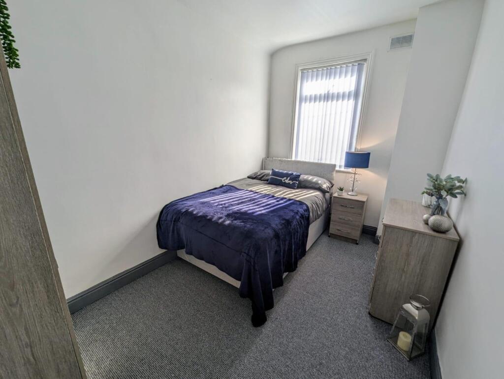 A neatly arranged double bedroom featuring a co...