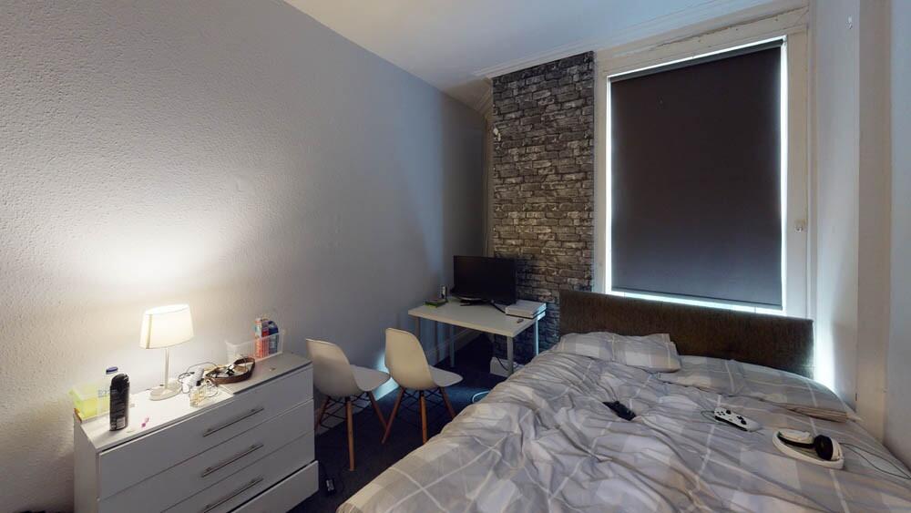 A cozy bedroom featuring a bed, desk with chair...