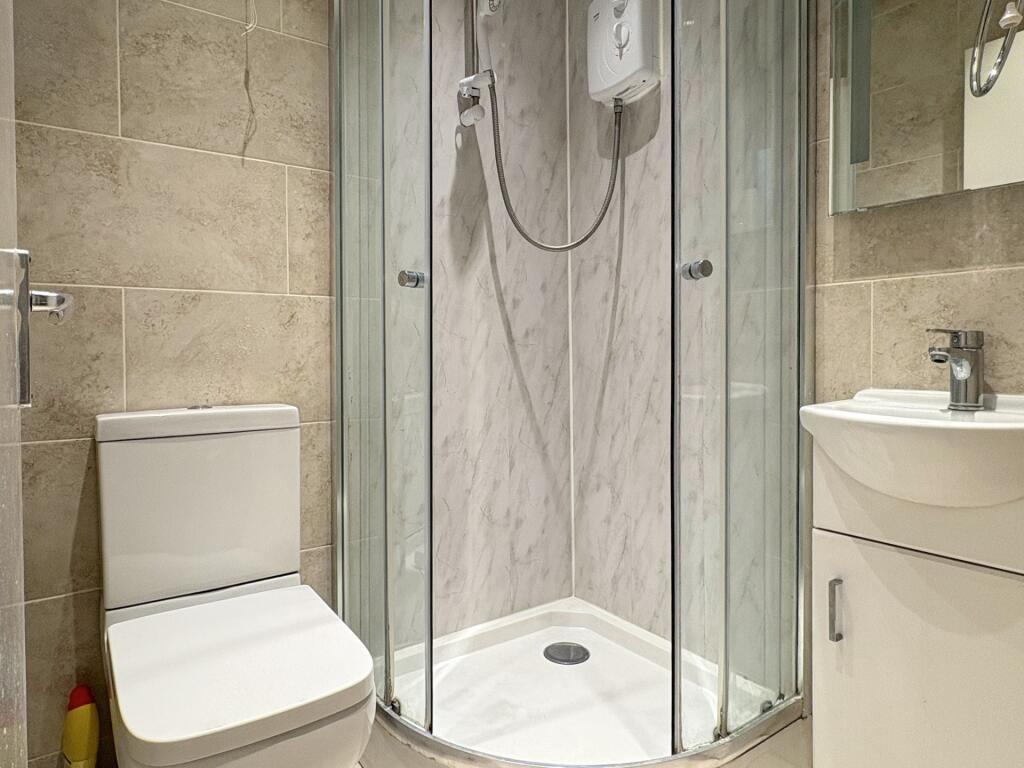 Modern tiled bathroom with a curved glass corne...