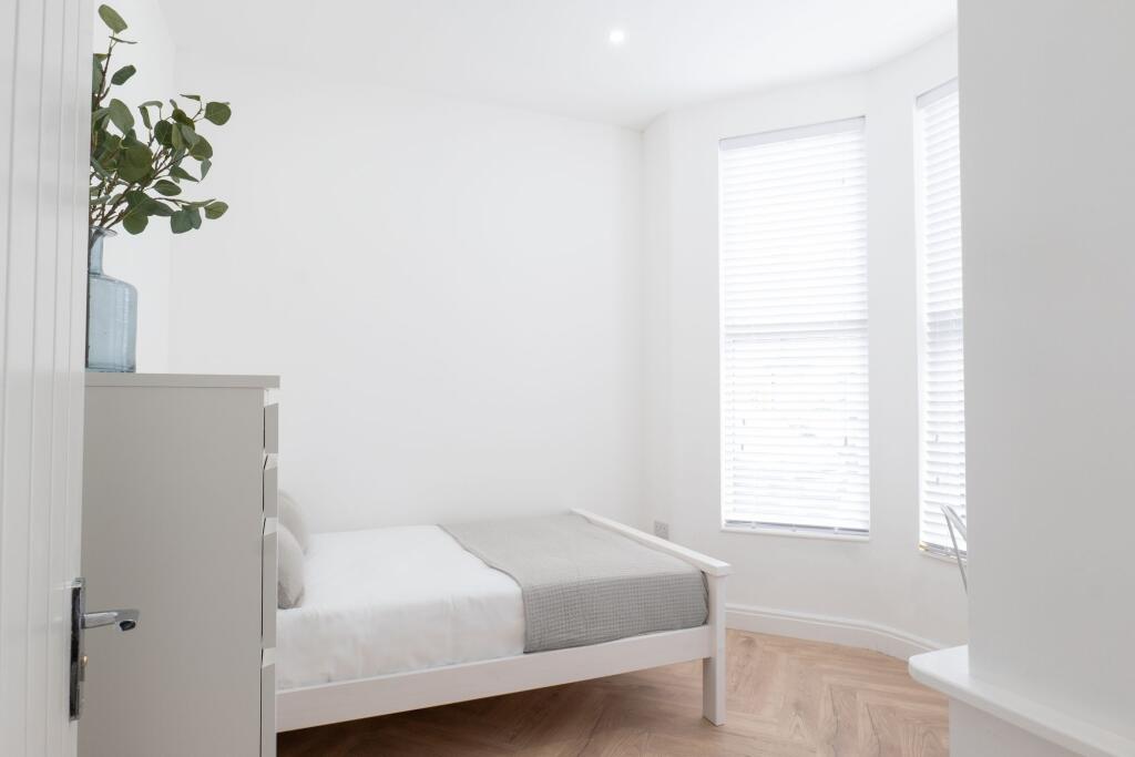 A bright and minimalist single bedroom featurin...