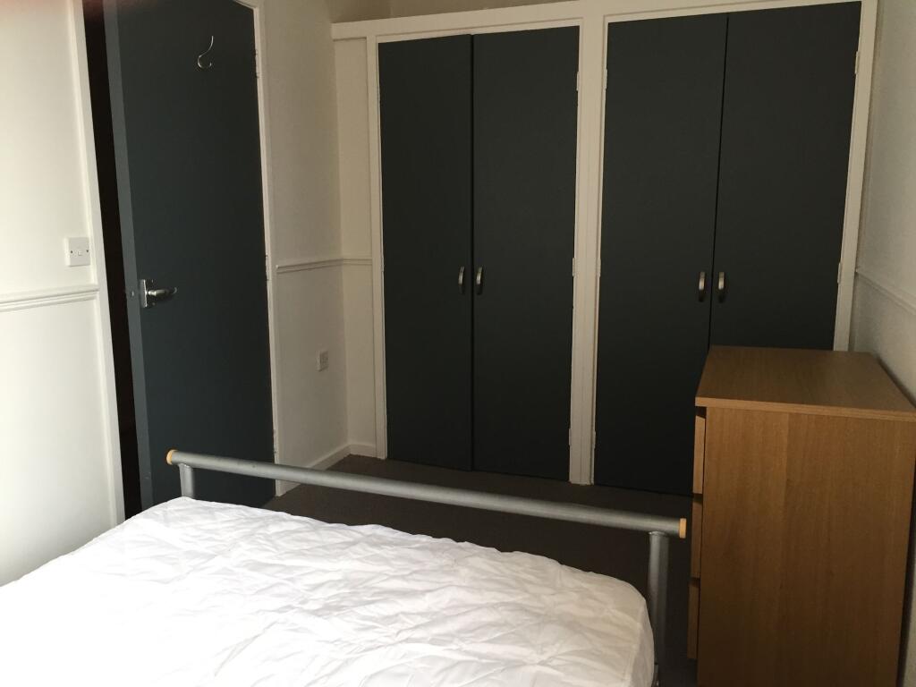 A tidy bedroom featuring a metal bed frame with...