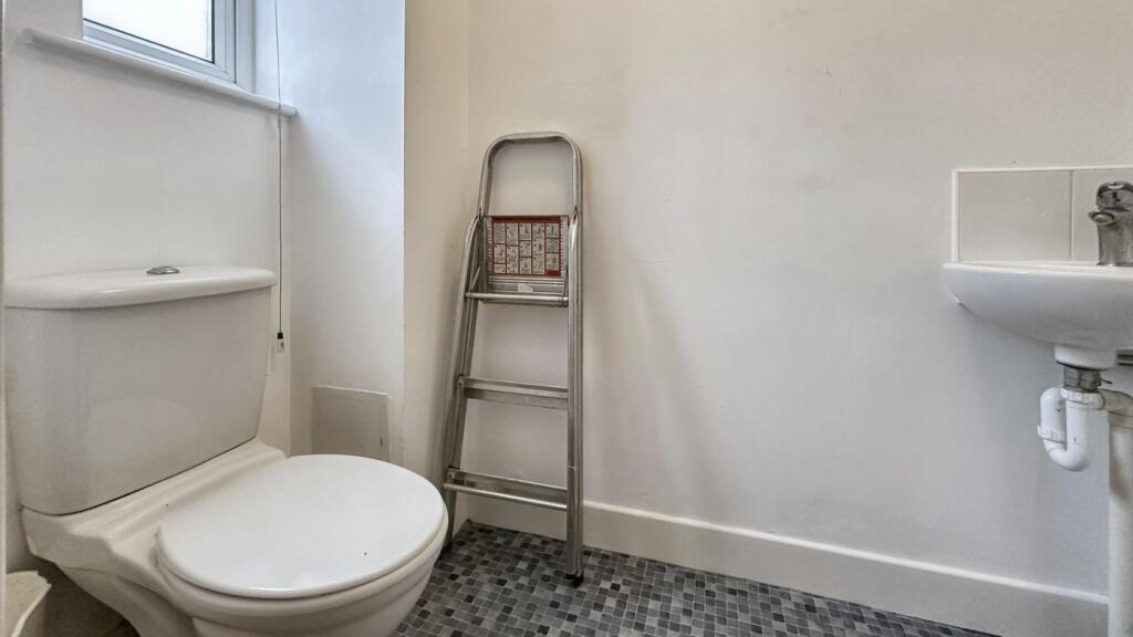 A clean but small bathroom featuring a shower a...