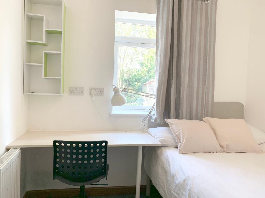 A bright and tidy single bedroom featuring a co...