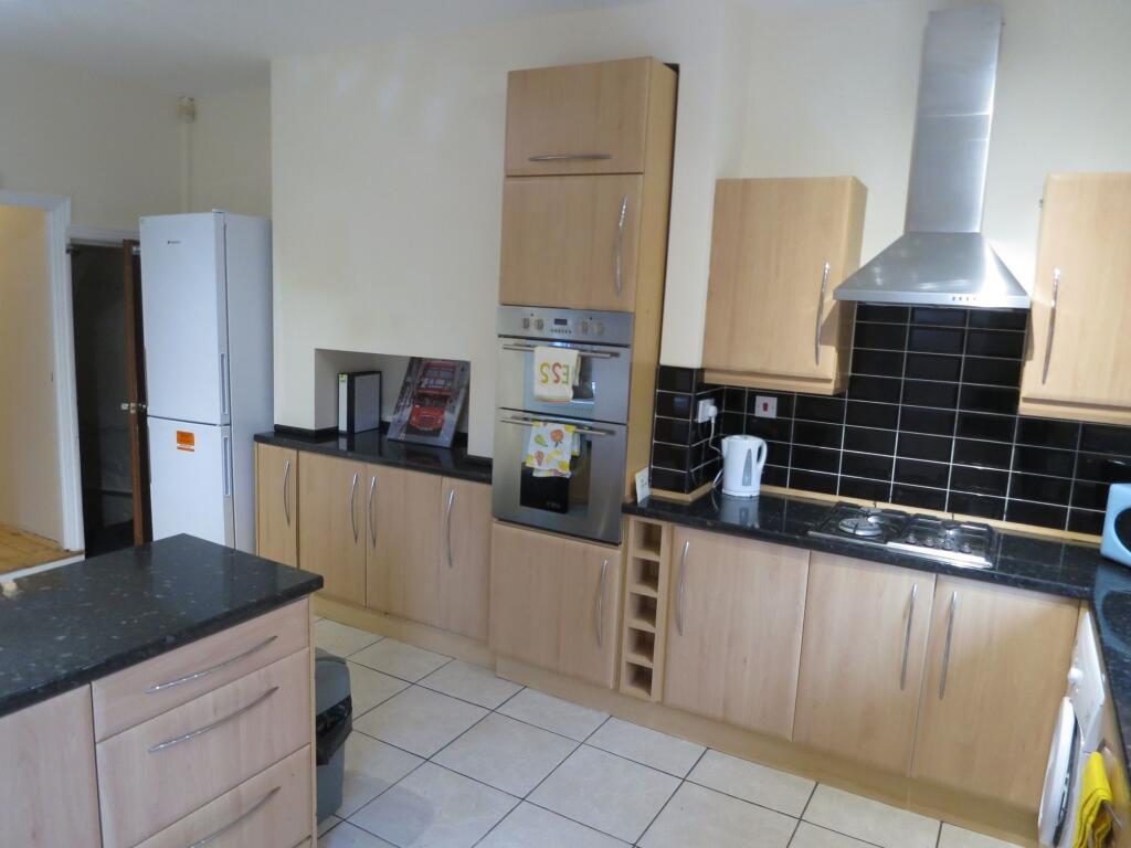 Modern kitchen with wooden cabinets, black coun...