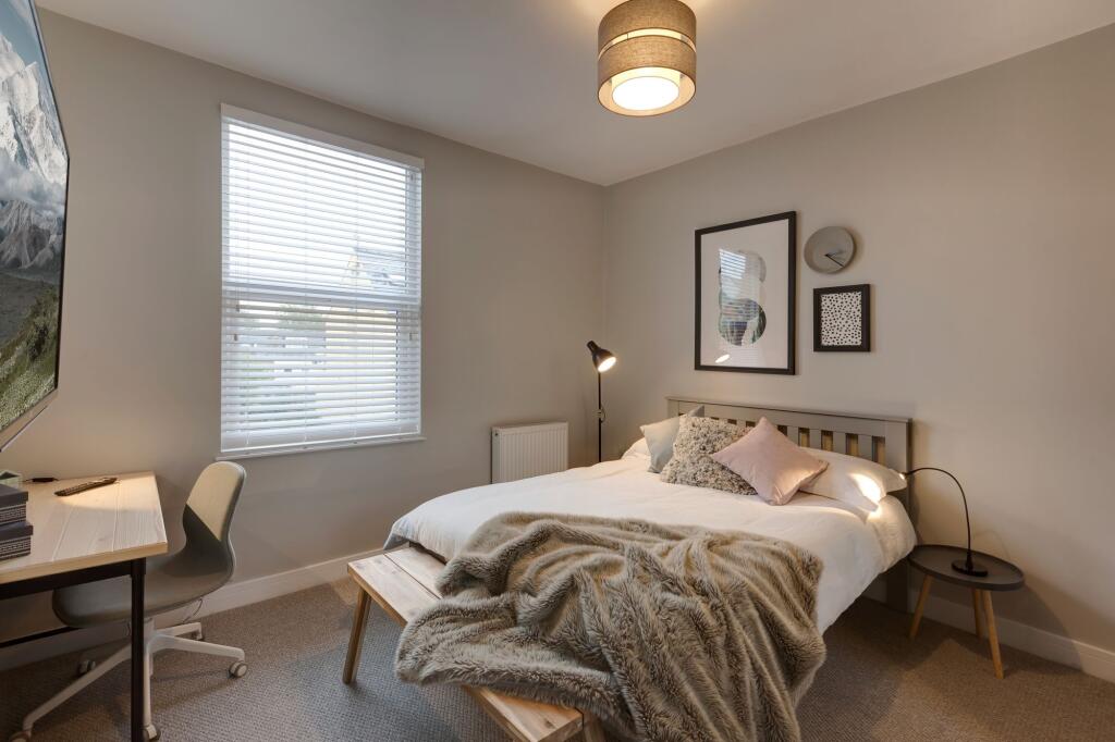 A stylish and welcoming bedroom featuring a lar...