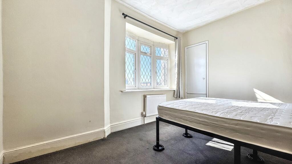 A bright double bedroom featuring a large windo...