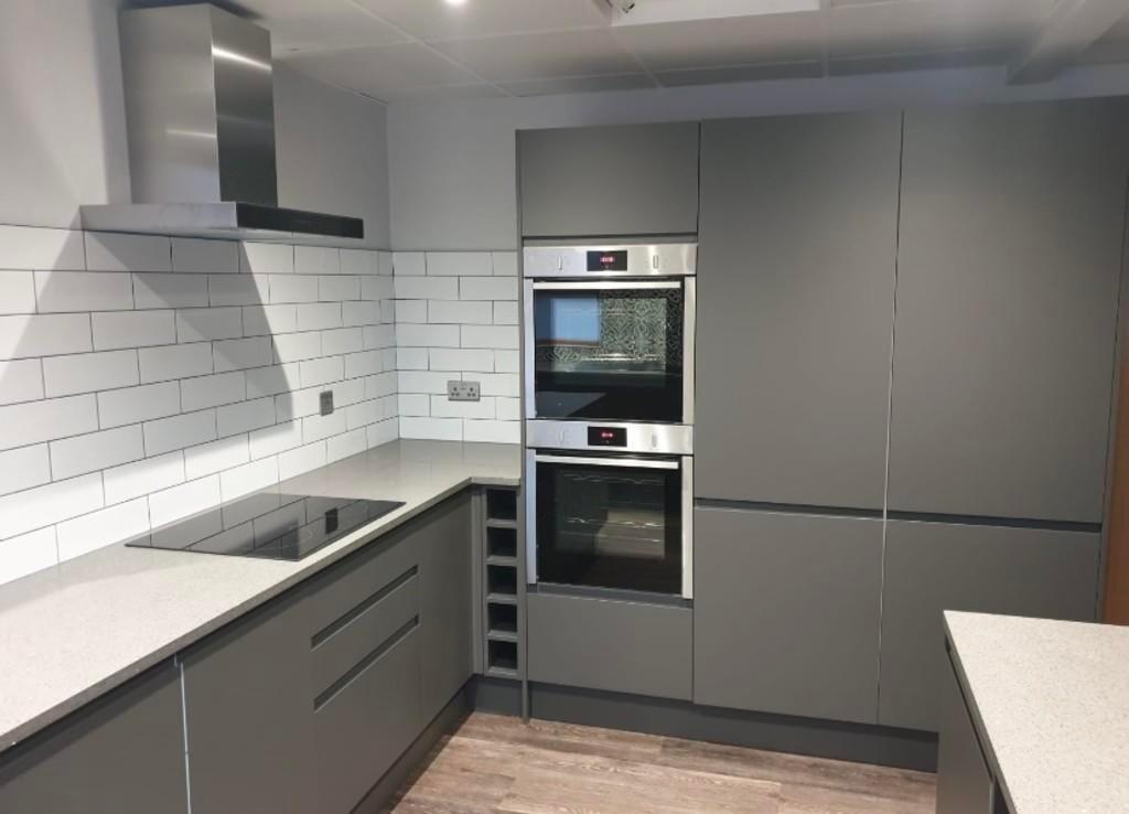 A modern and sleek kitchen featuring grey cabin...
