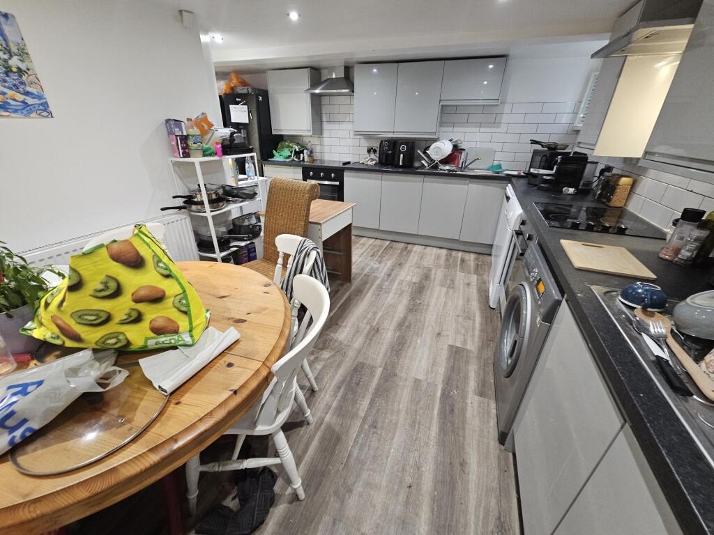 Modern kitchen with ample white cabinetry, stai...