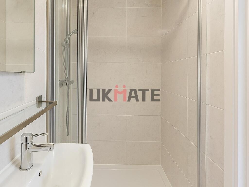 Clean, modern bathroom with neutral tiles, a sh...