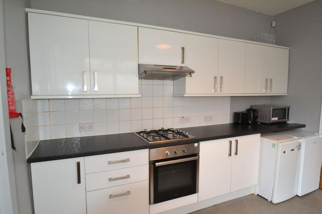 A modern kitchen featuring sleek white cabinets...
