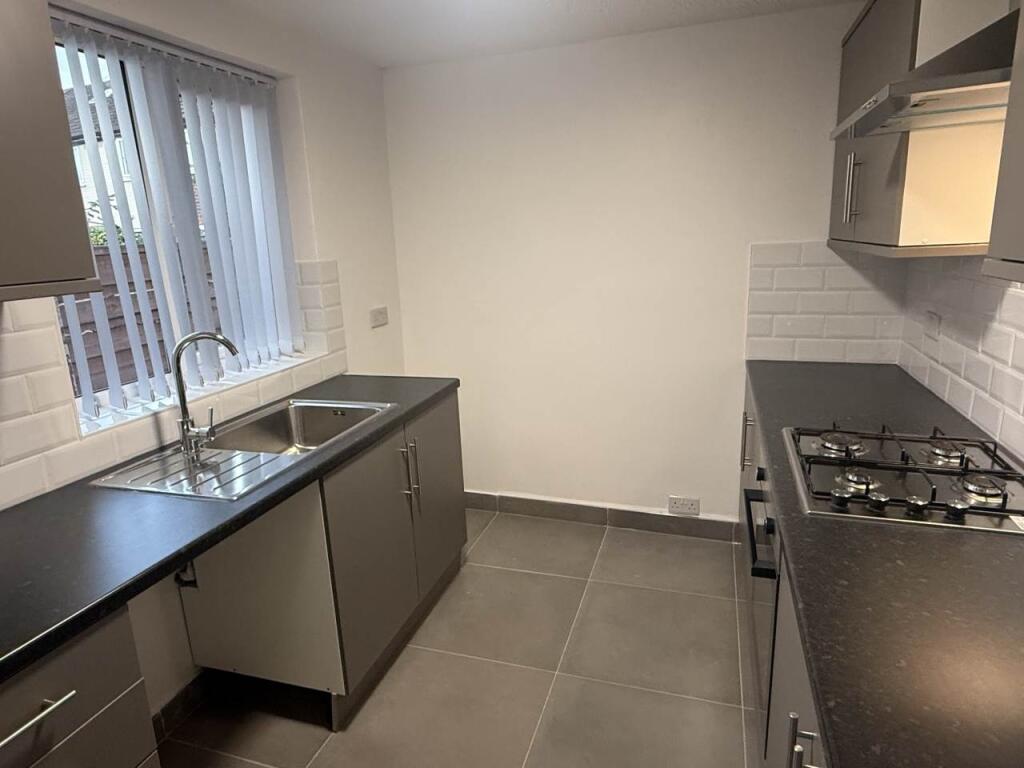 A modern, well-lit kitchen with sleek counterto...