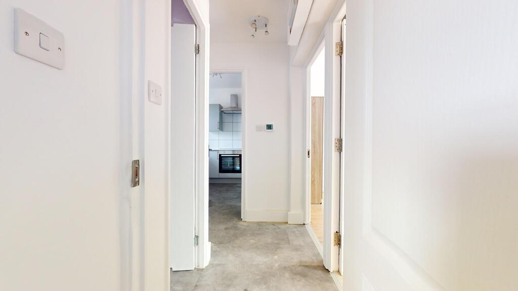 Bright and clean hallway with white walls leadi...