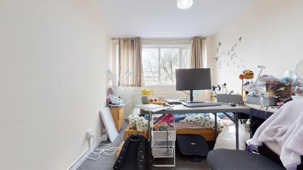 A compact bedroom featuring a large window that...