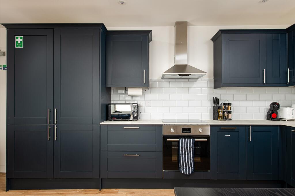 This modern kitchen features sleek navy cabinet...