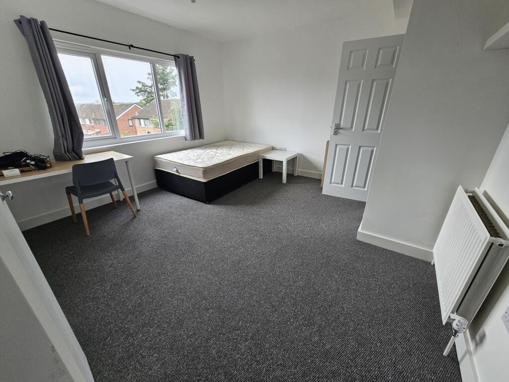 A spacious, bright bedroom featuring a large wi...