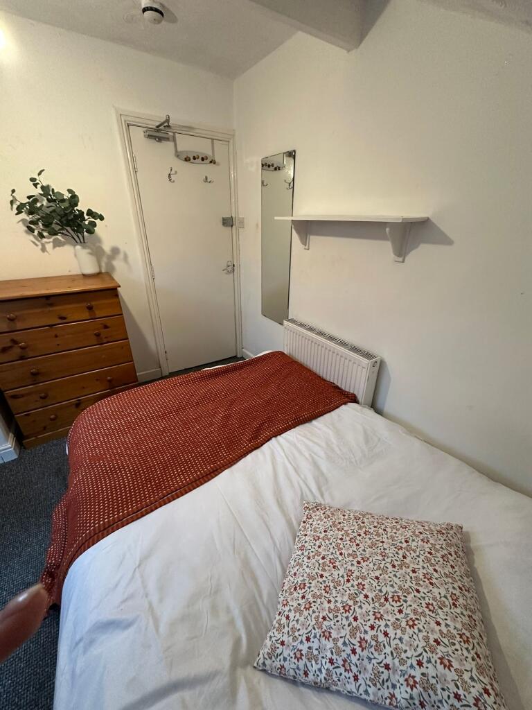 A modest bedroom with a neatly made bed featuri...