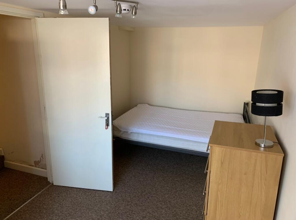 A tidy single bedroom featuring a bed and a dre...