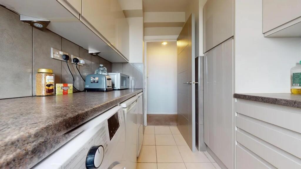 A clean and modern galley kitchen featuring sle...