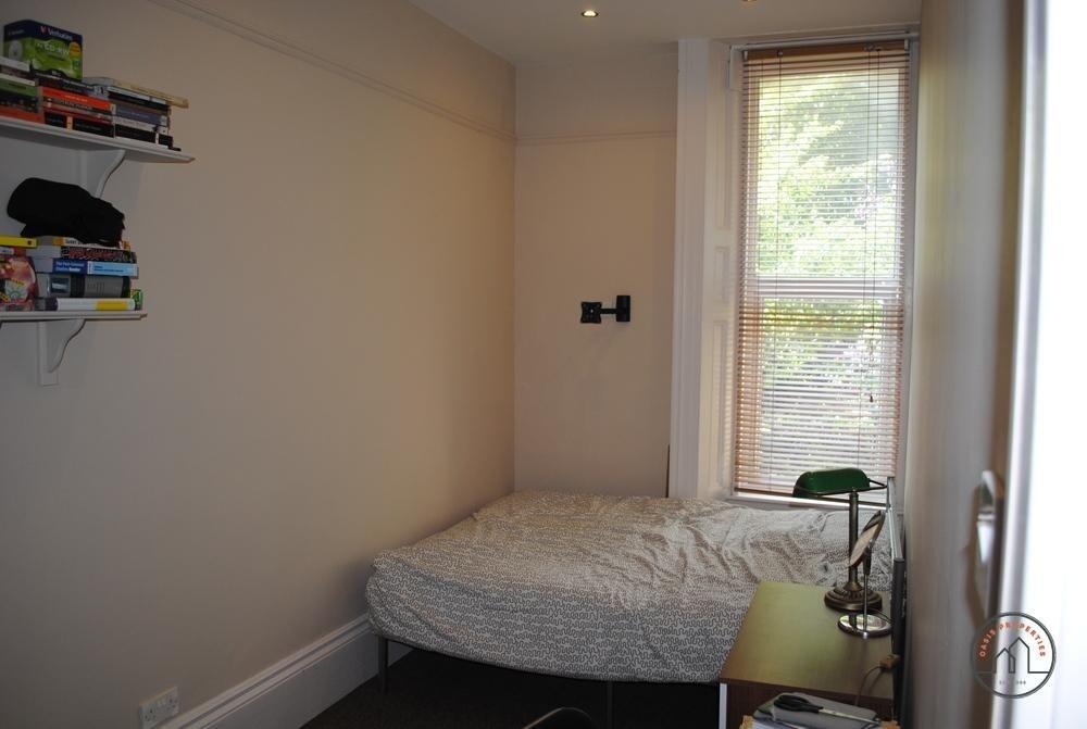 A cozy student bedroom featuring a single bed b...