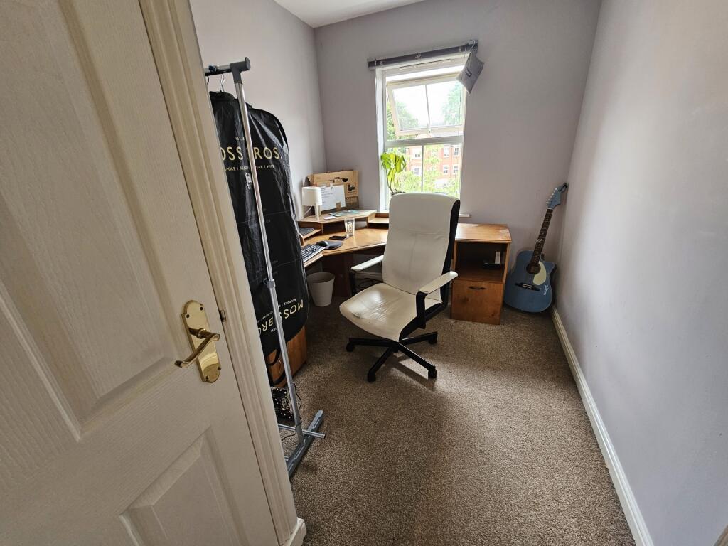 Cozy single bedroom featuring a comfortable des...