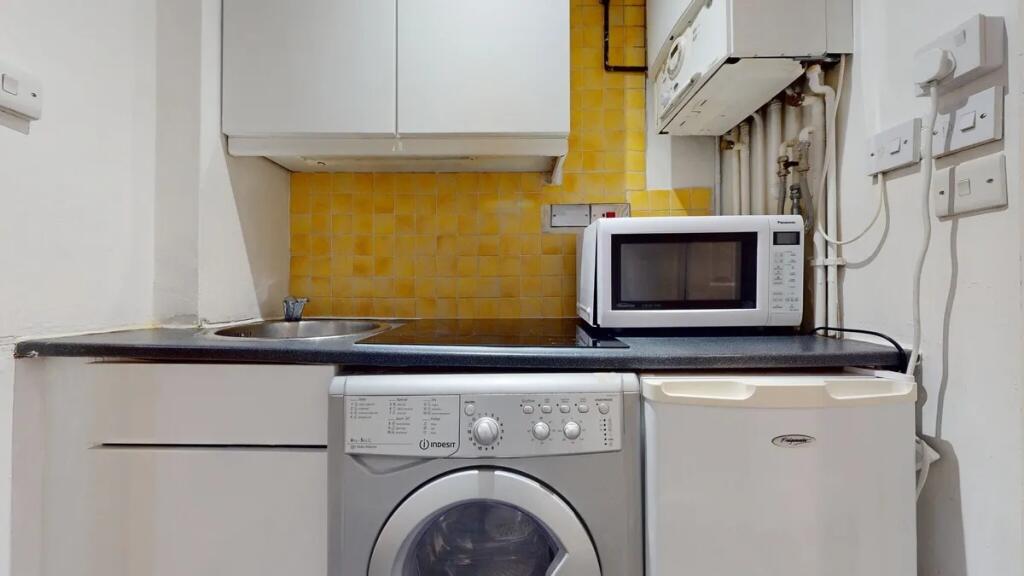 Compact kitchen area featuring essential applia...