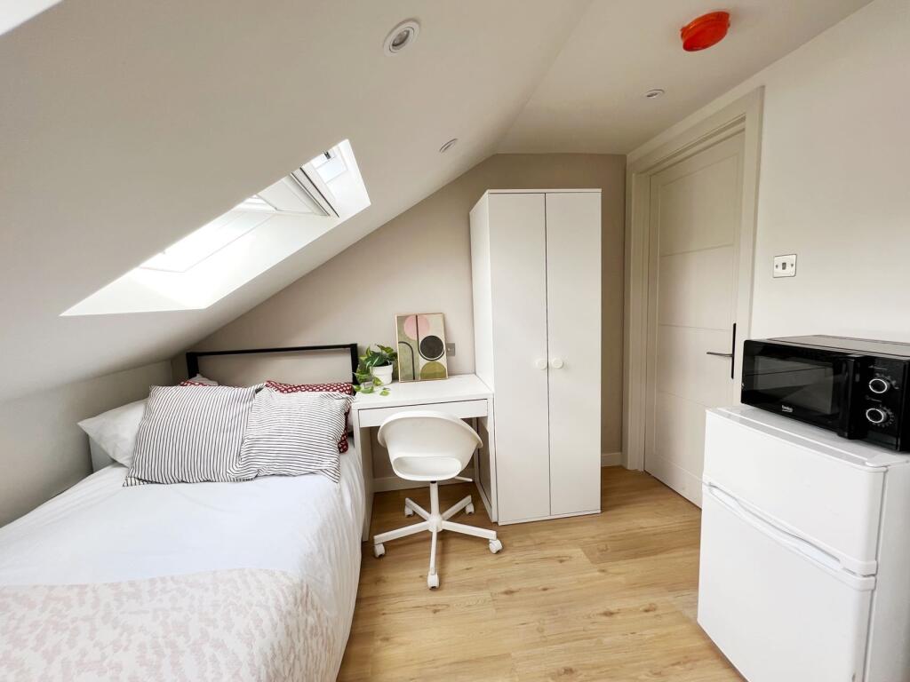 Bright and cozy single bedroom featuring a skyl...