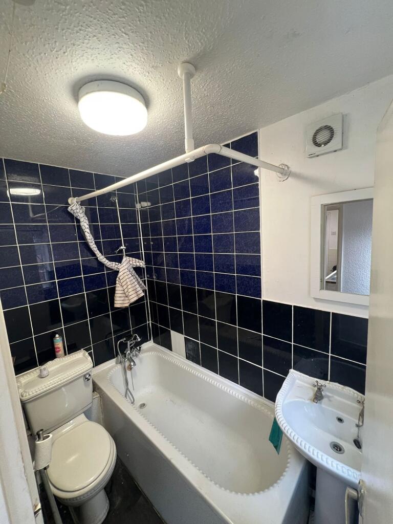 A compact bathroom suite featuring a white bath...