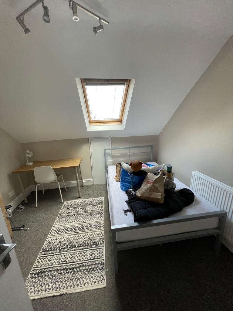 A cozy single bedroom featuring a sloped ceilin...