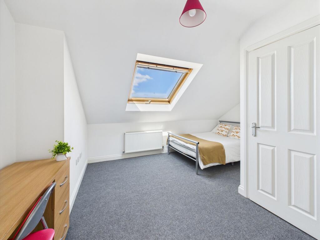 Bright and airy bedroom featuring a large skyli...
