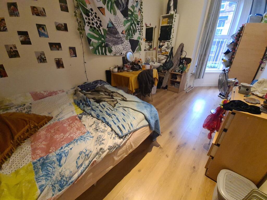 A cozy single bedroom featuring a bright wooden...