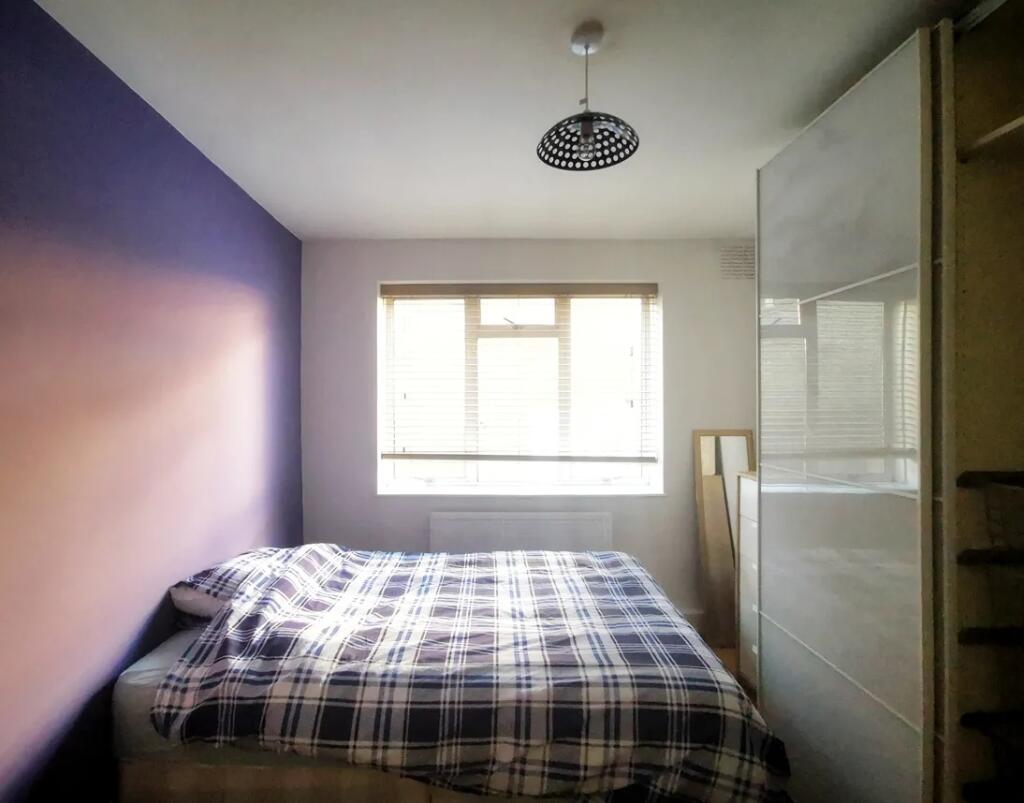 A cozy double bedroom featuring a stylish plaid...
